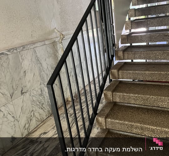 מעקה מתכת שחור ליד מדרגות בטון